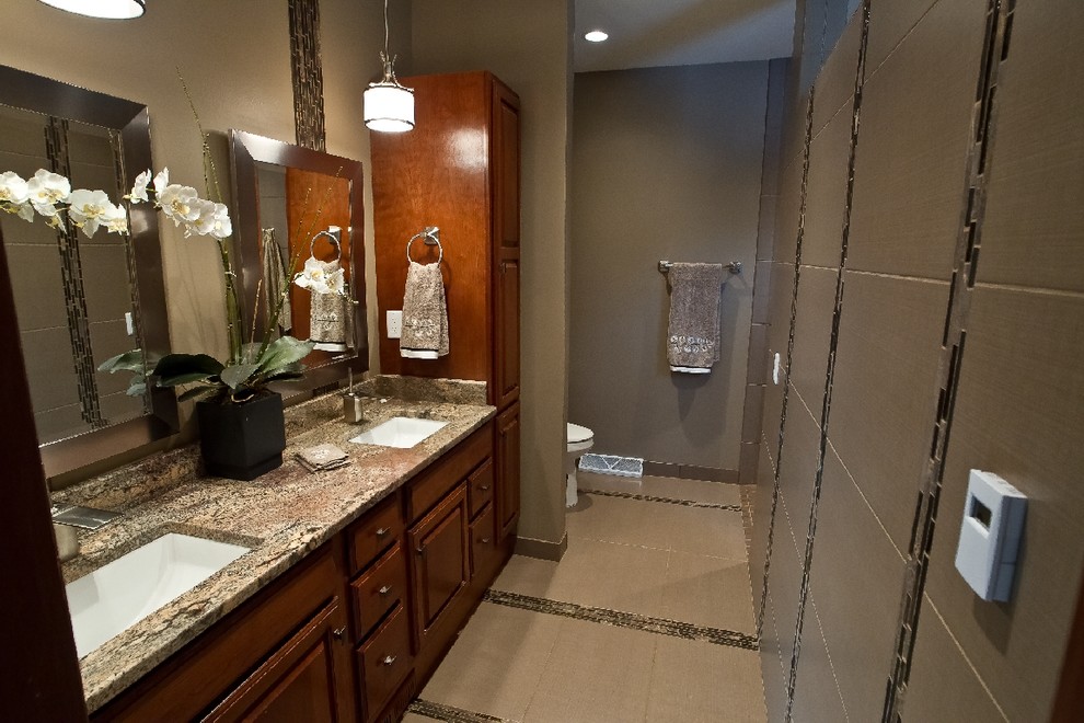 Cette image montre une salle de bain principale traditionnelle en bois brun de taille moyenne avec un lavabo encastré, un placard avec porte à panneau surélevé, un plan de toilette en granite, une douche à l'italienne, WC séparés, un carrelage gris, des carreaux de porcelaine, un mur gris et un sol en carrelage de porcelaine.