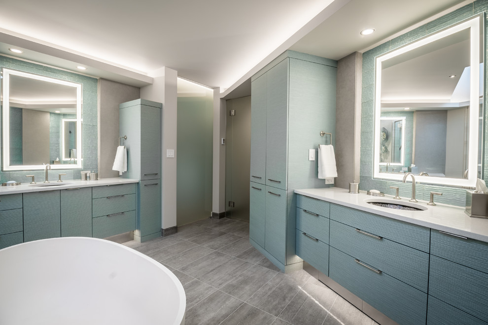 Exemple d'une salle de bain principale tendance avec un placard en trompe-l'oeil, des portes de placard turquoises, une baignoire indépendante, une douche double, WC à poser, un carrelage vert, un carrelage en pâte de verre, un mur gris, un sol en carrelage de céramique, un lavabo encastré, un plan de toilette en quartz modifié, un sol gris et une cabine de douche à porte battante.
