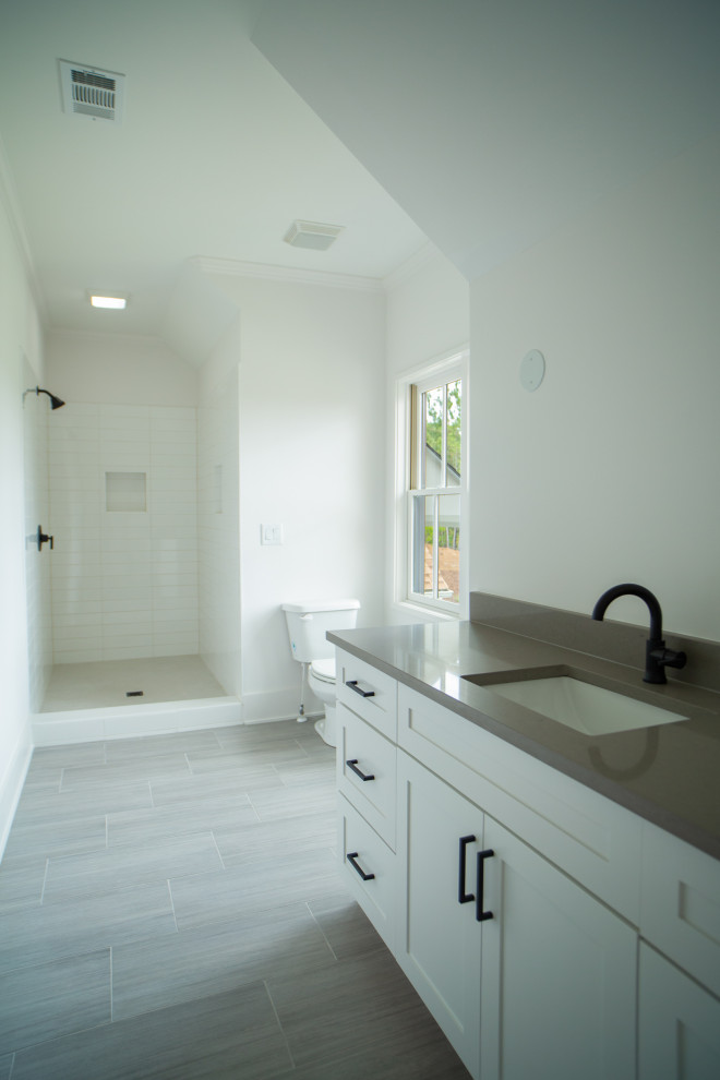 Inspiration för ett mellanstort lantligt grå grått badrum, med möbel-liknande, vita skåp, en dusch i en alkov, en toalettstol med separat cisternkåpa, vit kakel, keramikplattor, vita väggar, klinkergolv i keramik, ett undermonterad handfat, bänkskiva i kvarts, grått golv och med dusch som är öppen