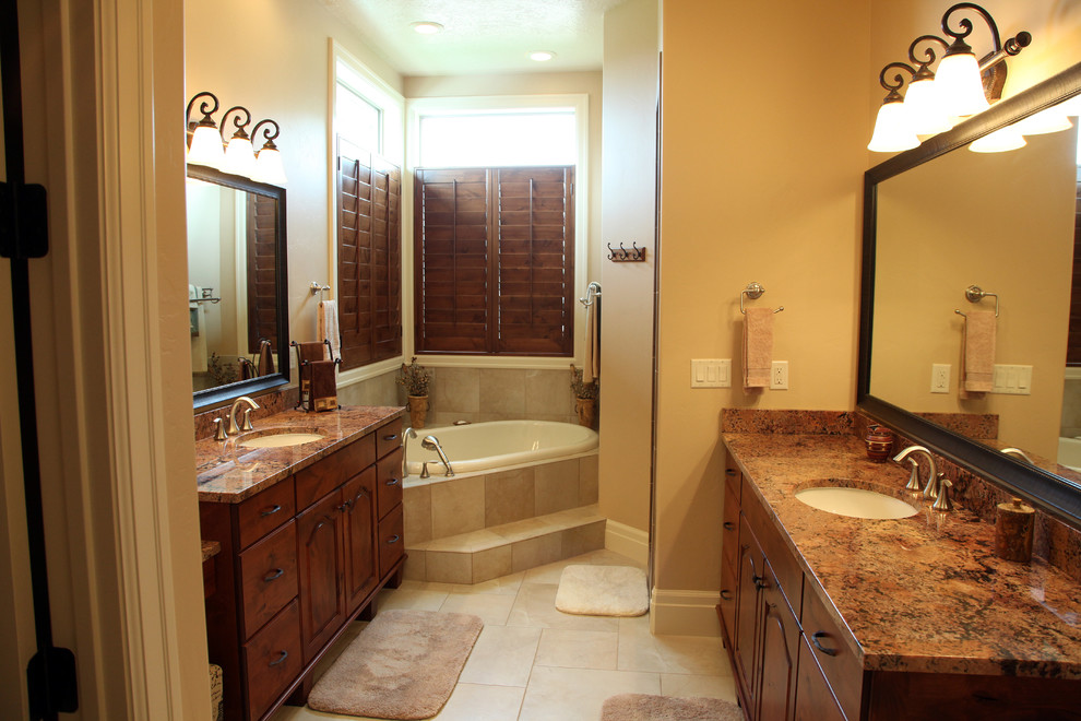 Klassisk inredning av ett mellanstort en-suite badrum, med ett undermonterad handfat, luckor med upphöjd panel, skåp i mellenmörkt trä, granitbänkskiva, ett platsbyggt badkar, en dusch i en alkov, beige kakel, porslinskakel, beige väggar och klinkergolv i porslin
