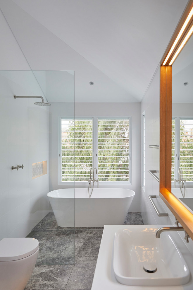 Modernes Duschbad mit freistehender Badewanne, Nasszelle, weißer Wandfarbe, Einbauwaschbecken, grauem Boden, offener Dusche und grauer Waschtischplatte in Sonstige