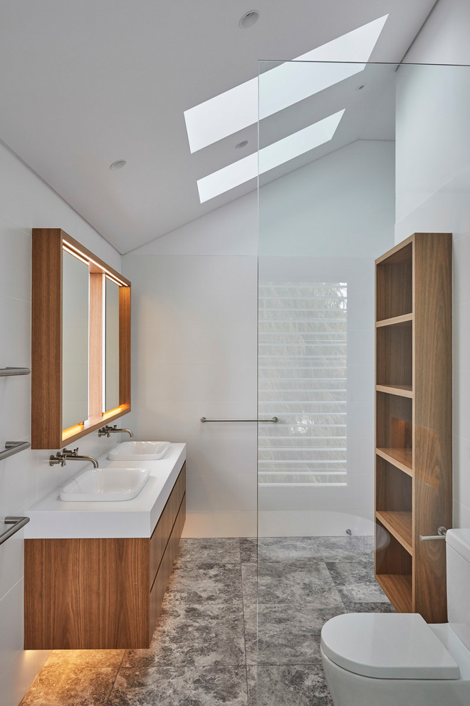 Inspiration för moderna vitt badrum med dusch, med släta luckor, skåp i mellenmörkt trä, vita väggar, ett nedsänkt handfat och grått golv