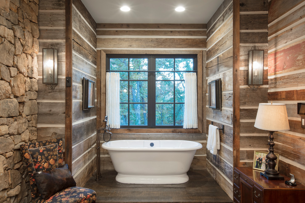 Imagen de cuarto de baño principal rural con bañera exenta, paredes marrones, suelo de madera oscura, suelo marrón y piedra