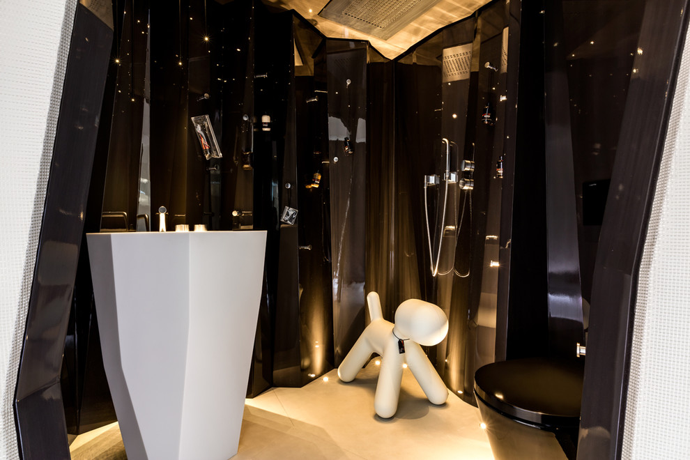 Inspiration för små moderna en-suite badrum, med en kantlös dusch, en vägghängd toalettstol, svart kakel, glasskiva, svarta väggar, betonggolv och ett konsol handfat