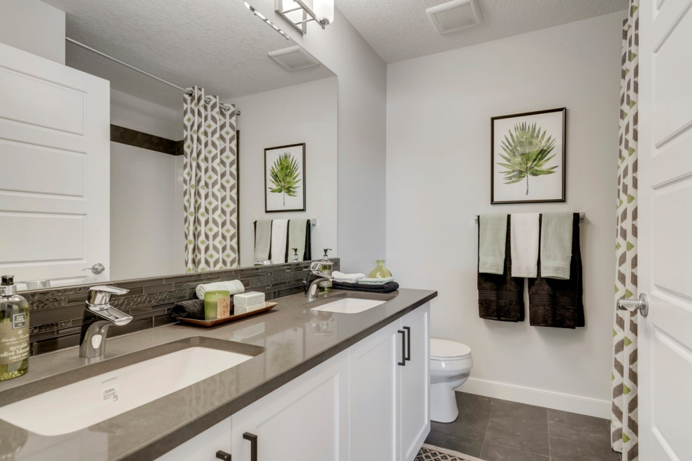 This is an example of a medium sized classic family bathroom in Calgary with shaker cabinets, white cabinets, a one-piece toilet, black tiles, glass tiles, white walls, ceramic flooring, a submerged sink, engineered stone worktops, grey floors, grey worktops, double sinks and a built in vanity unit.