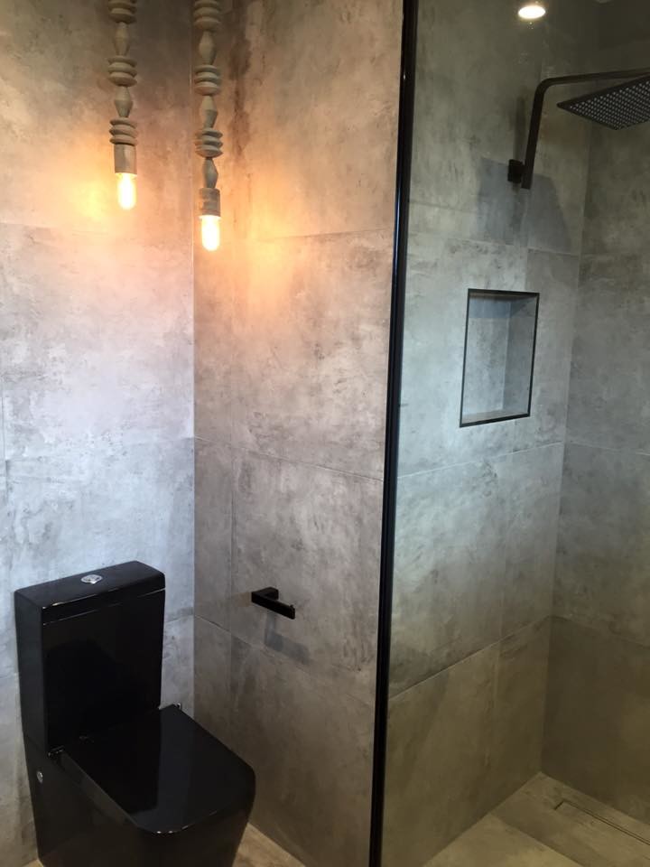 Foto de cuarto de baño principal urbano de tamaño medio con puertas de armario negras, ducha abierta, sanitario de una pieza, baldosas y/o azulejos grises, baldosas y/o azulejos de cemento, paredes grises, suelo de azulejos de cemento y lavabo sobreencimera