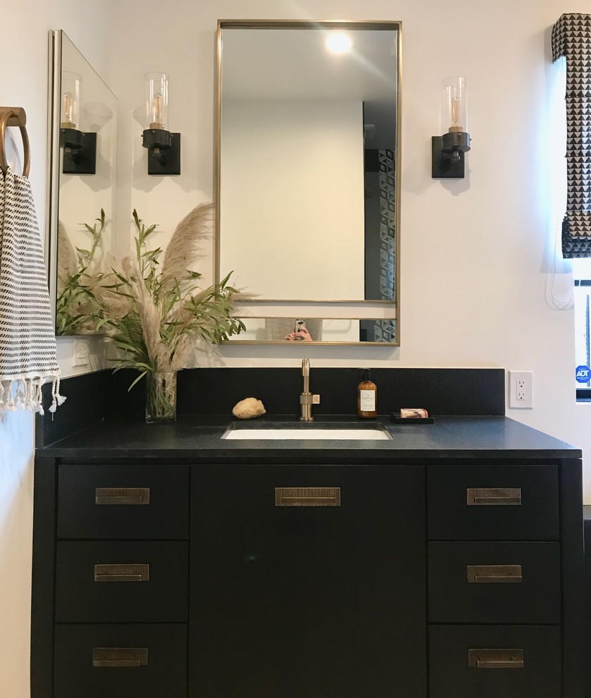 Photo of a large classic ensuite bathroom in Orange County with flat-panel cabinets, black cabinets, a freestanding bath, an alcove shower, a one-piece toilet, black tiles, marble tiles, white walls, limestone flooring, a submerged sink, granite worktops, beige floors, a hinged door and black worktops.