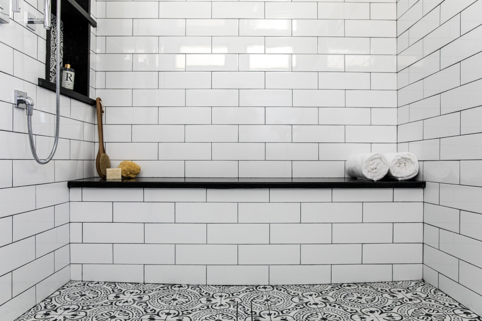 Inredning av ett klassiskt svart svart badrum med dusch, med luckor med infälld panel, vita skåp, en kantlös dusch, en toalettstol med separat cisternkåpa, vit kakel, keramikplattor, gröna väggar, cementgolv, ett fristående handfat, bänkskiva i kvartsit och med dusch som är öppen