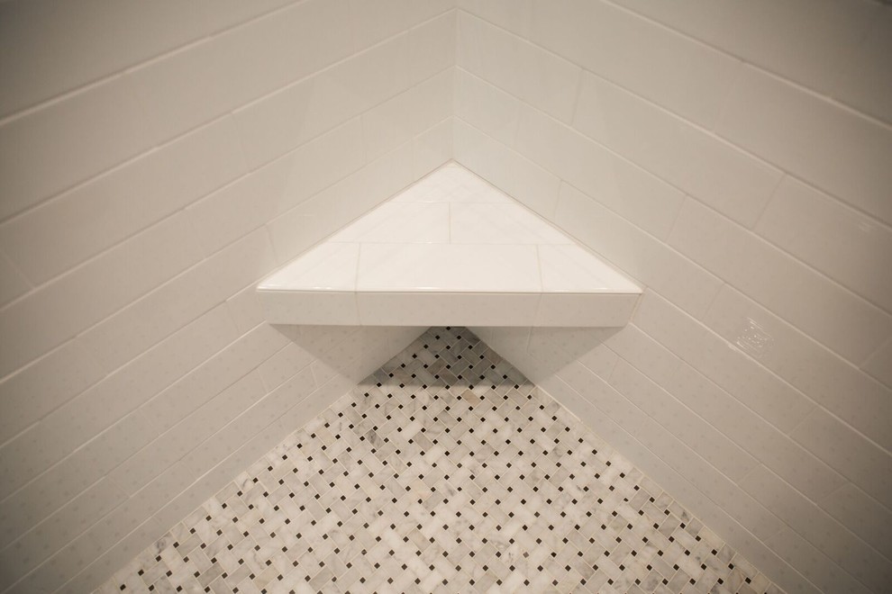 Inredning av ett modernt mellanstort badrum med dusch, med en dusch i en alkov, svart och vit kakel, porslinskakel, klinkergolv i porslin, luckor med infälld panel, vita skåp, en toalettstol med hel cisternkåpa, vita väggar, ett undermonterad handfat och marmorbänkskiva