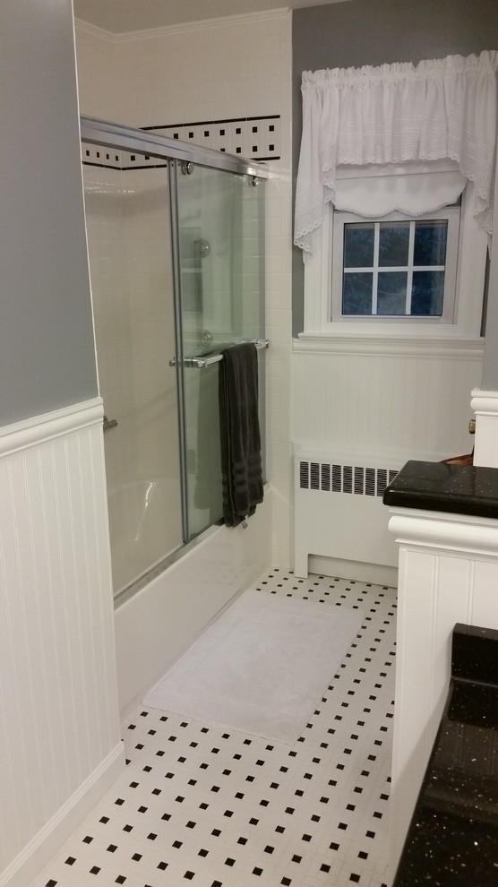 На фото: главная ванная комната среднего размера в стиле ретро с душем над ванной, черно-белой плиткой, серыми стенами, полом из керамической плитки, плоскими фасадами, белыми фасадами, унитазом-моноблоком, керамической плиткой, врезной раковиной и столешницей из гранита