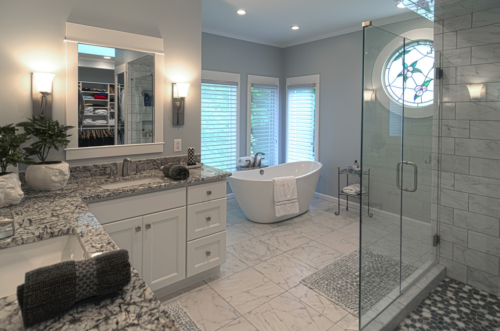 Inspiration for a medium sized contemporary ensuite bathroom in Cincinnati with white cabinets, a freestanding bath, a corner shower, a one-piece toilet, black and white tiles, marble tiles, grey walls, marble flooring, a submerged sink, granite worktops, recessed-panel cabinets, white floors and a hinged door.