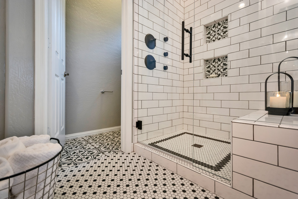 Пример оригинального дизайна: главная ванная комната среднего размера в стиле неоклассика (современная классика) с фасадами в стиле шейкер, белыми фасадами, угловым душем, белой плиткой, плиткой кабанчик, серыми стенами, полом из мозаичной плитки, врезной раковиной, столешницей из гранита, белым полом, душем с распашными дверями и черной столешницей