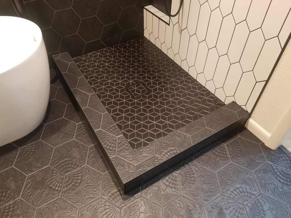 Medium sized modern ensuite bathroom in Denver with flat-panel cabinets, white cabinets, a freestanding bath, a corner shower, black and white tiles, porcelain tiles, black walls, porcelain flooring, solid surface worktops, black floors, a hinged door and white worktops.