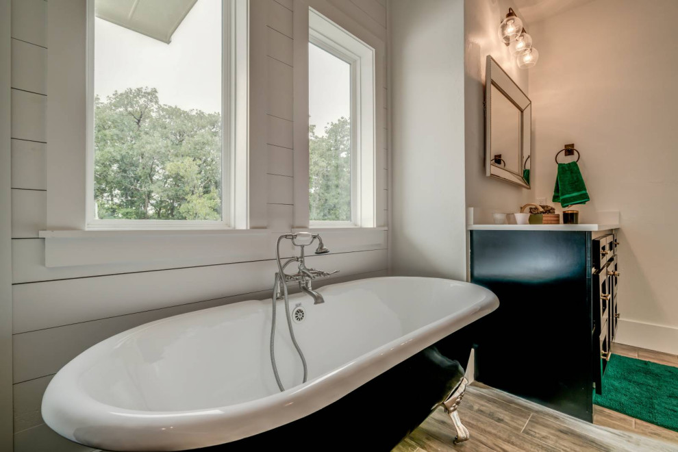 Cette photo montre une salle de bain principale nature avec des portes de placard noires, une baignoire sur pieds et un mur blanc.