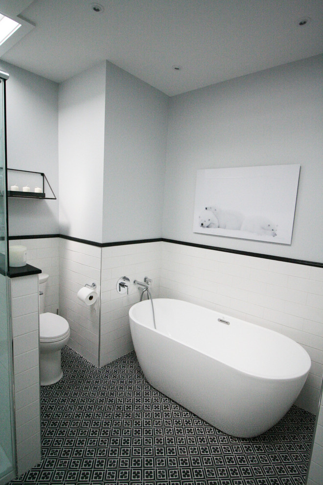 Klassisk inredning av ett mellanstort grå grått en-suite badrum, med skåp i shakerstil, vita skåp, ett fristående badkar, en hörndusch, en toalettstol med hel cisternkåpa, vit kakel, keramikplattor, grå väggar, cementgolv, ett undermonterad handfat, marmorbänkskiva, svart golv och dusch med gångjärnsdörr
