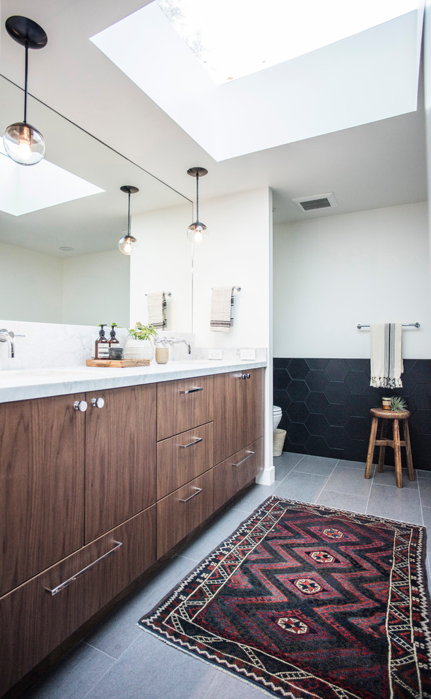 Cette photo montre une salle de bain moderne avec un carrelage noir, des carreaux de céramique et un mur blanc.