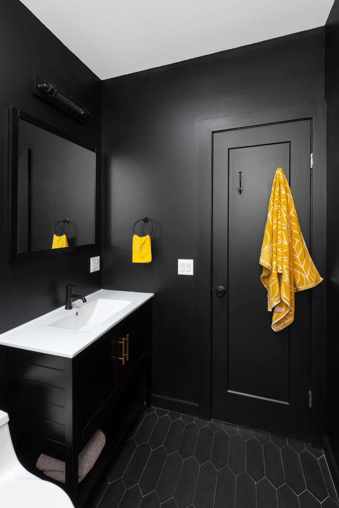 Mid-sized urban 3/4 gray tile and subway tile cement tile floor and black floor bathroom photo in New York with a one-piece toilet, black cabinets, black walls, an integrated sink, white countertops, recessed-panel cabinets and solid surface countertops