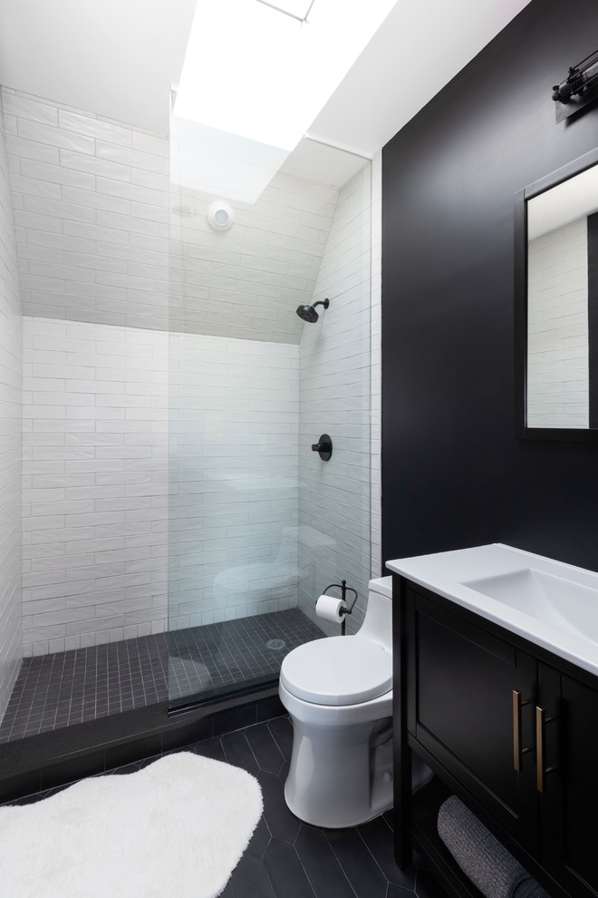 Inspiration för mellanstora industriella vitt badrum med dusch, med en dusch i en alkov, en toalettstol med hel cisternkåpa, cementgolv, med dusch som är öppen, luckor med infälld panel, svarta skåp, grå kakel, tunnelbanekakel, svarta väggar, ett integrerad handfat, bänkskiva i akrylsten och svart golv