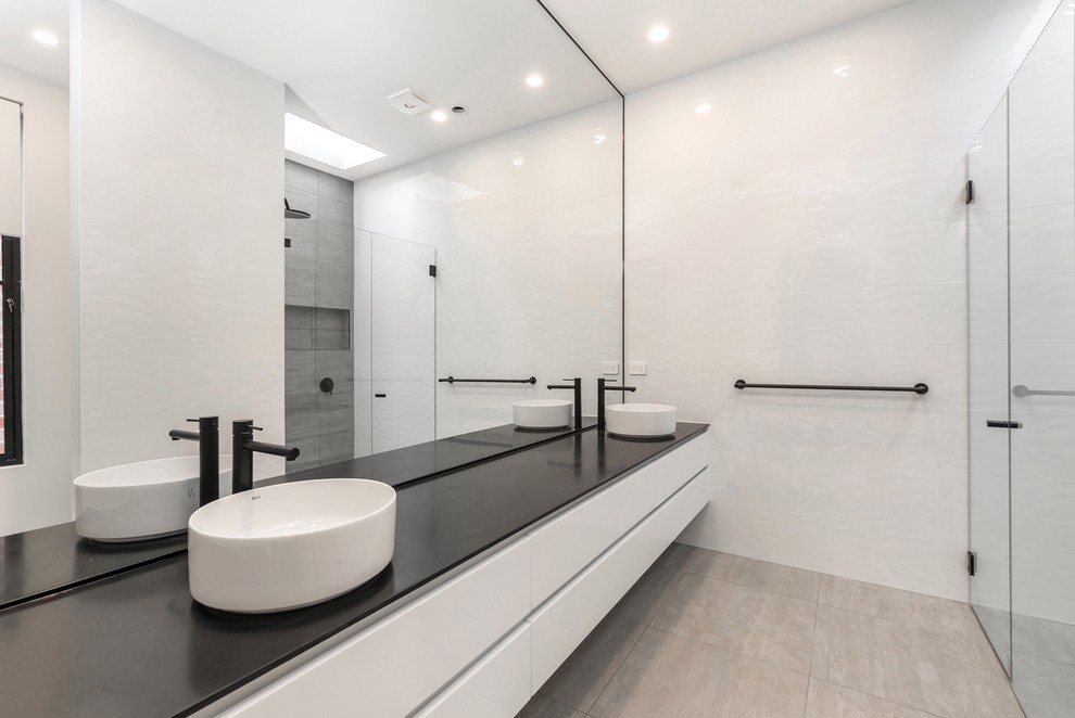 Réalisation d'une salle de bain minimaliste de taille moyenne avec des portes de placard blanches, un carrelage blanc, un mur blanc, un sol gris et une cabine de douche à porte battante.