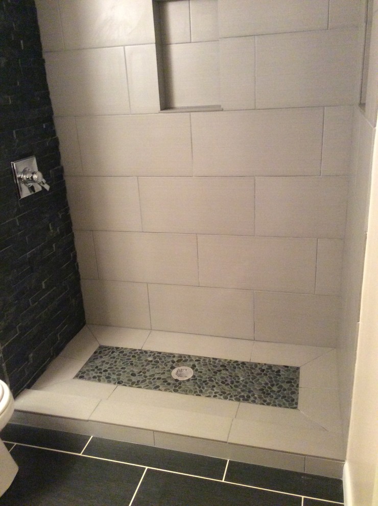 Cette photo montre une petite salle d'eau moderne avec une douche ouverte, un carrelage noir et blanc, une plaque de galets, un mur blanc et un sol en carrelage de porcelaine.