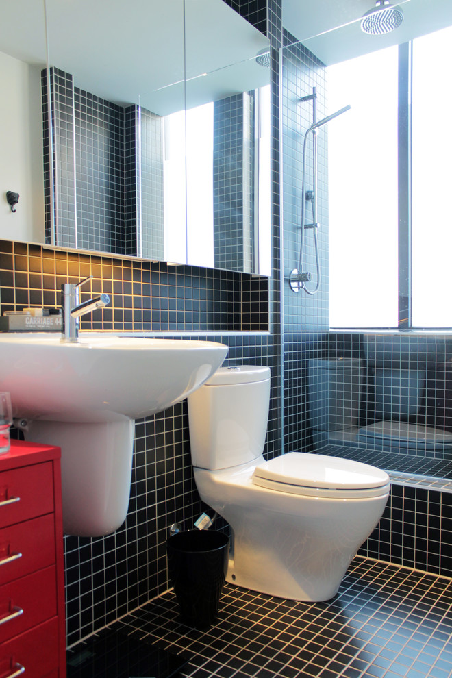 Foto på ett funkis badrum, med ett väggmonterat handfat, en dusch i en alkov, en toalettstol med separat cisternkåpa, svart kakel, mosaik och röda skåp