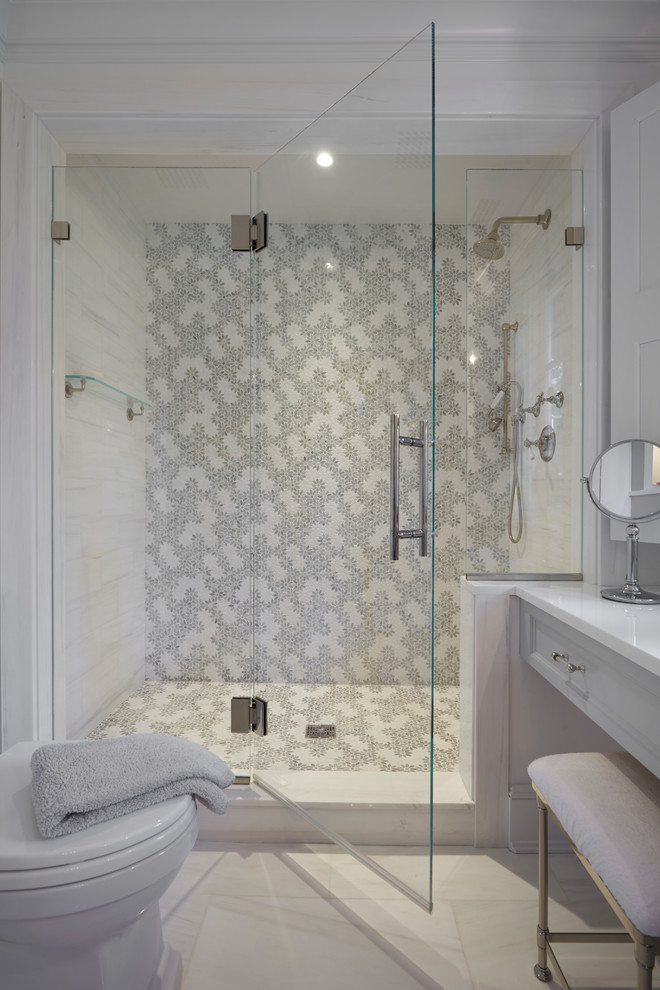 Klassisk inredning av ett badrum, med en hörndusch, marmorgolv, ett undermonterad handfat, bänkskiva i glas och dusch med gångjärnsdörr