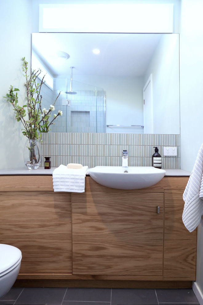 Diseño de cuarto de baño minimalista pequeño con armarios con paneles lisos, puertas de armario de madera clara, ducha esquinera, sanitario de una pieza, baldosas y/o azulejos multicolor, baldosas y/o azulejos en mosaico, paredes verdes y suelo de baldosas de cerámica