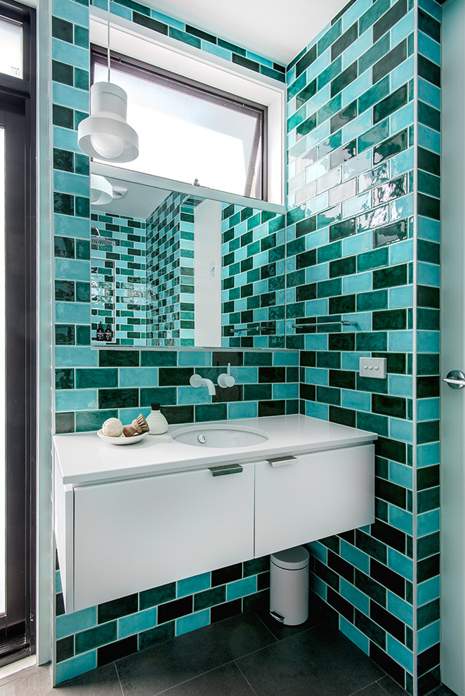 Cette image montre une salle de bain design avec un placard à porte plane, des portes de placard blanches, un carrelage bleu, un carrelage vert, un carrelage multicolore, un carrelage métro, un lavabo encastré et un sol gris.