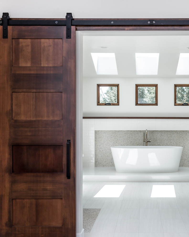 Свежая идея для дизайна: большая главная ванная комната в стиле неоклассика (современная классика) с отдельно стоящей ванной, бежевой плиткой, галечной плиткой, белыми стенами и полом из керамогранита - отличное фото интерьера