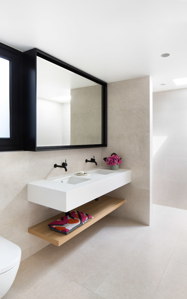 Trendy beige tile beige floor bathroom photo in Melbourne with a wall-mount toilet, beige walls, an undermount sink and white countertops