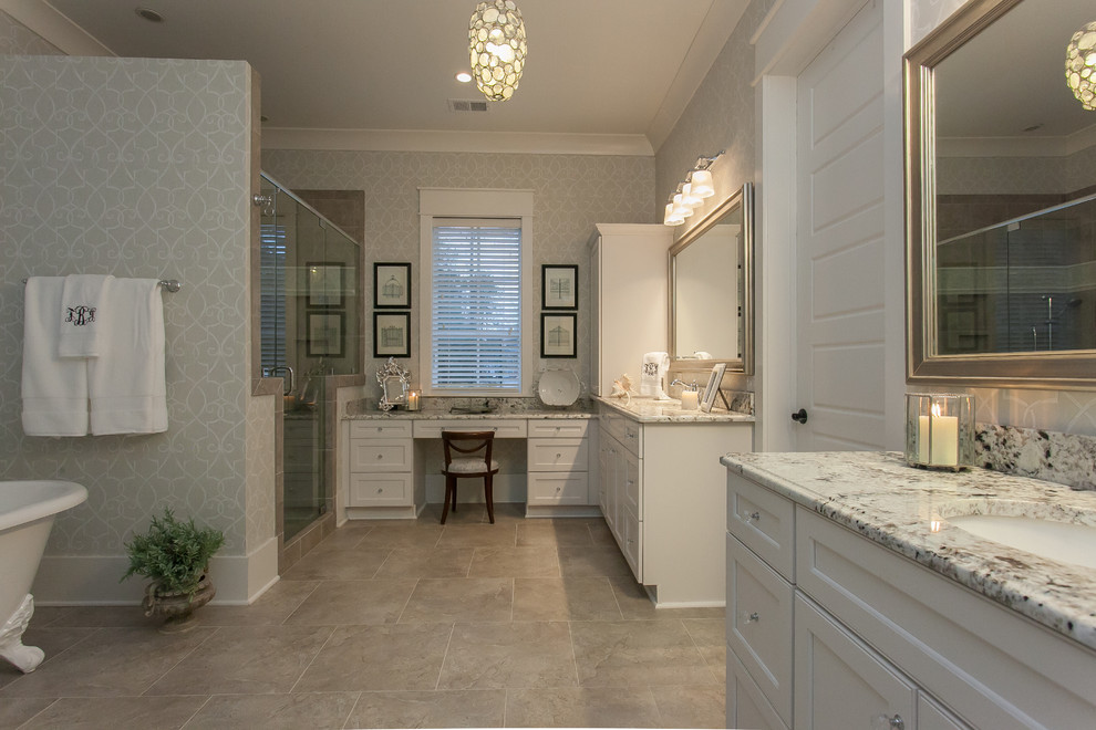 Modelo de cuarto de baño clásico renovado grande con lavabo encastrado, armarios con paneles empotrados, puertas de armario blancas, encimera de granito, bañera exenta, baldosas y/o azulejos grises y suelo de travertino