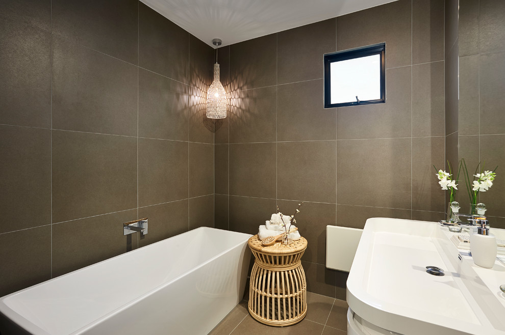 Exempel på ett modernt badrum, med ett fristående badkar, brun kakel, bruna väggar och ett avlångt handfat