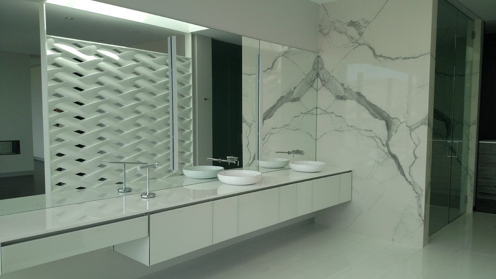 Inspiration for a large contemporary ensuite bathroom in Las Vegas with flat-panel cabinets, white cabinets, a freestanding bath, an alcove shower, grey tiles, white tiles, marble tiles, white walls, a vessel sink, quartz worktops, white floors and a hinged door.