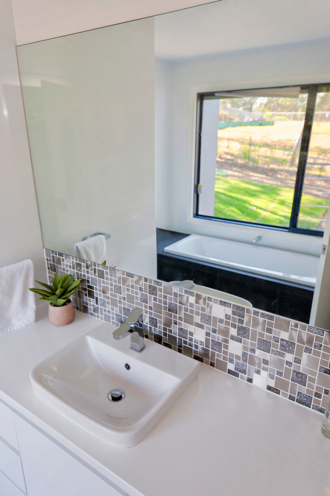 Свежая идея для дизайна: ванная комната в современном стиле с накладной раковиной, белыми фасадами, накладной ванной, серой плиткой и белыми стенами - отличное фото интерьера