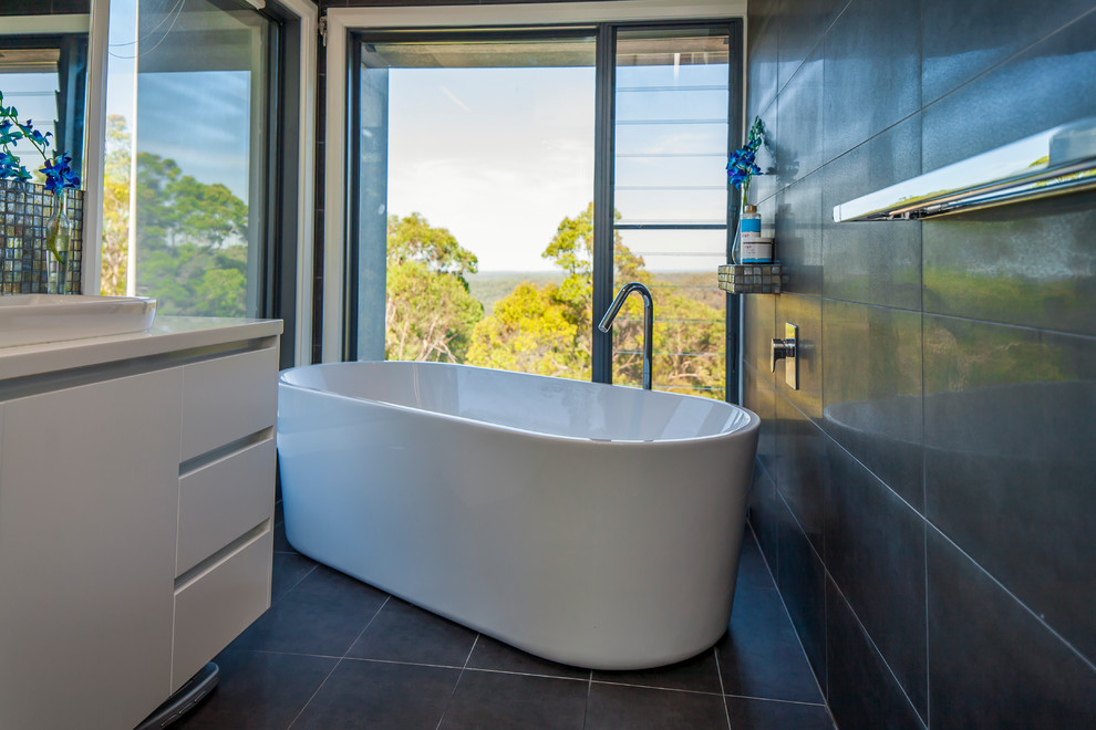 Diseño de cuarto de baño contemporáneo con lavabo encastrado, puertas de armario blancas, bañera exenta, baldosas y/o azulejos grises y paredes blancas