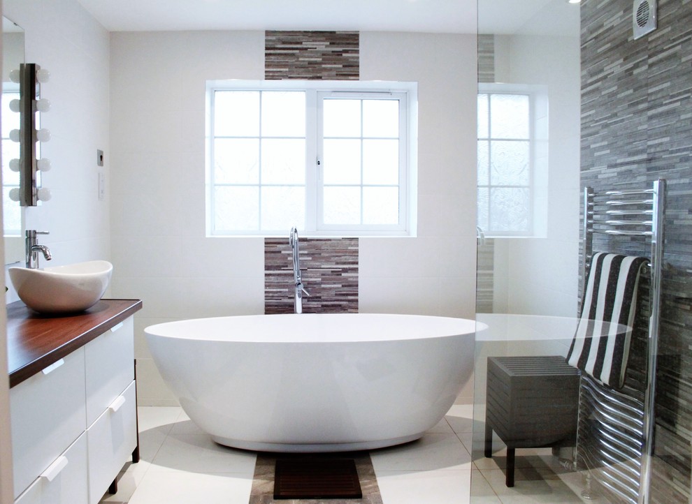 Inspiration for a small modern family bathroom in Buckinghamshire with flat-panel cabinets, white cabinets, a freestanding bath, a walk-in shower, a wall mounted toilet, grey tiles, stone tiles, white walls, porcelain flooring, a vessel sink and wooden worktops.