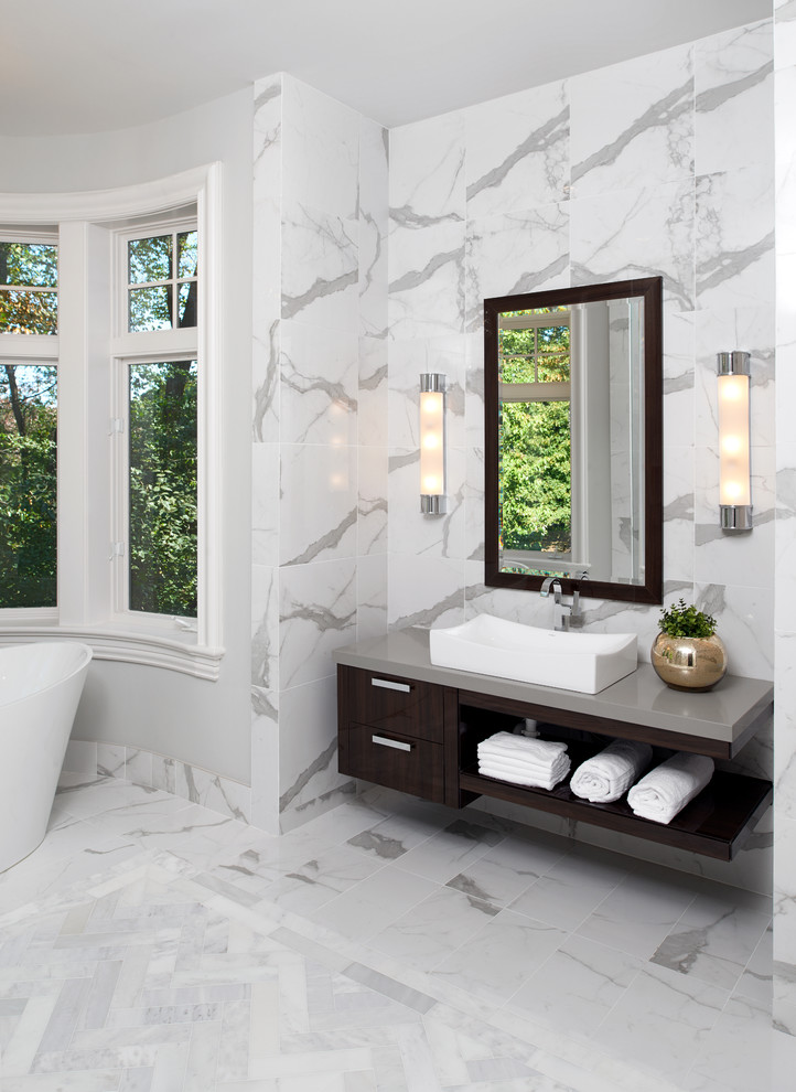 Photo of a large contemporary ensuite bathroom in Detroit with flat-panel cabinets, brown cabinets, a freestanding bath, a built-in shower, a one-piece toilet, white tiles, marble tiles, white walls, marble flooring, a pedestal sink, concrete worktops, white floors and a hinged door.