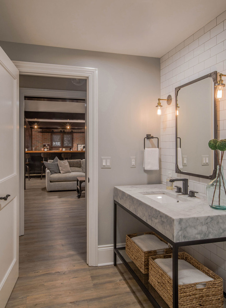 Inspiration for a mid-sized industrial 3/4 white tile and subway tile vinyl floor and beige floor alcove shower remodel in Detroit with open cabinets, black cabinets, a one-piece toilet, white walls, an undermount sink, marble countertops, a hinged shower door and white countertops