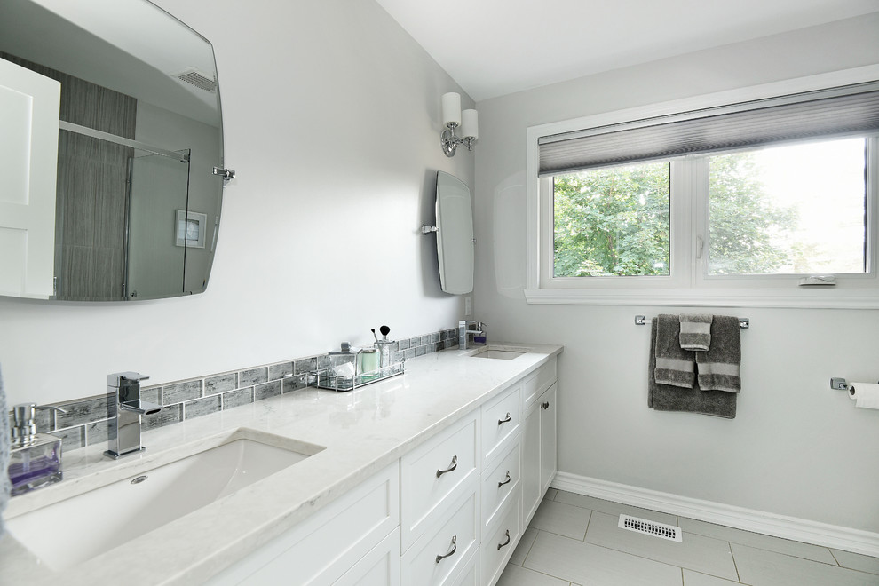 Пример оригинального дизайна: главная ванная комната среднего размера в современном стиле с фасадами в стиле шейкер, белыми фасадами, ванной в нише, угловым душем, раздельным унитазом, разноцветной плиткой, плиткой мозаикой, серыми стенами, полом из керамической плитки, монолитной раковиной, столешницей из искусственного кварца, серым полом, душем с раздвижными дверями и белой столешницей