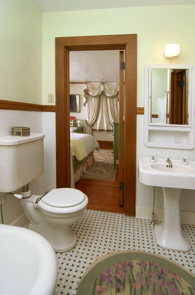 50 tals inredning av ett stort en-suite badrum, med ett piedestal handfat, ett badkar med tassar, flerfärgad kakel, porslinskakel, gröna väggar och klinkergolv i keramik