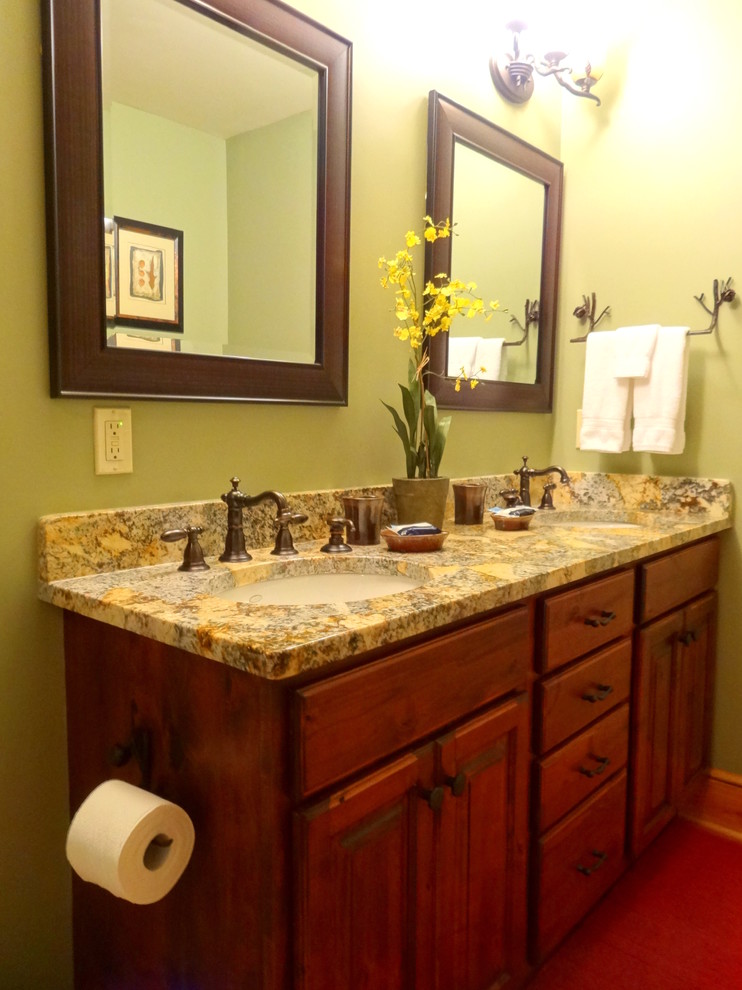 This is an example of a medium sized rustic ensuite bathroom in Charlotte with a submerged sink, raised-panel cabinets, dark wood cabinets, granite worktops, a corner bath, a shower/bath combination, a two-piece toilet, green walls and light hardwood flooring.