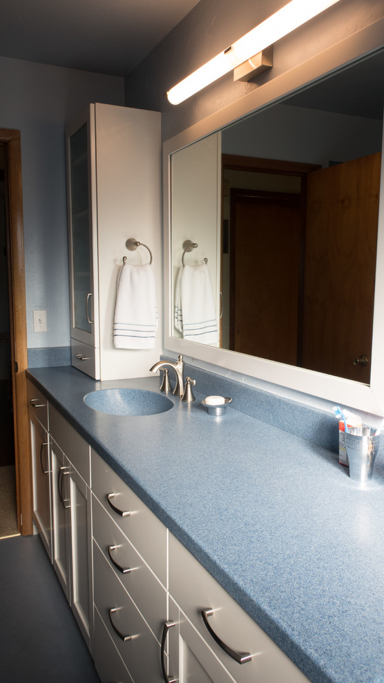 Inspiration pour une salle de bain design de taille moyenne avec un placard à porte shaker, des portes de placard blanches, WC séparés, un mur bleu, un sol en linoléum, un lavabo intégré, un plan de toilette en surface solide, un sol bleu et une cabine de douche avec un rideau.