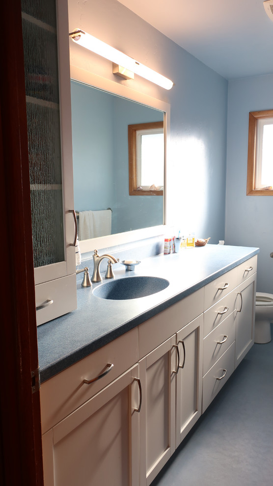 Idée de décoration pour une salle de bain design de taille moyenne avec un placard à porte shaker, des portes de placard blanches, WC séparés, un mur bleu, un sol en linoléum, un lavabo intégré, un plan de toilette en surface solide, un sol bleu et une cabine de douche avec un rideau.