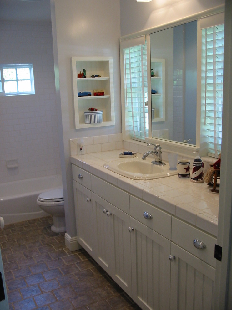 Medium sized nautical family bathroom in Los Angeles with a built-in sink, shaker cabinets, white cabinets, tiled worktops, an alcove bath, a shower/bath combination, white tiles, ceramic tiles, blue walls and porcelain flooring.