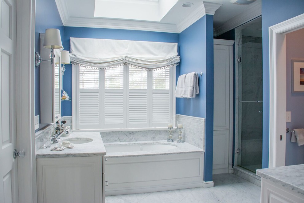 Example of a large classic master gray tile marble floor and gray floor corner shower design in Cleveland with furniture-like cabinets, white cabinets, an undermount tub, blue walls, marble countertops and a hinged shower door