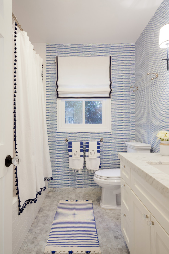 Idee per una stanza da bagno stile marinaro con ante con riquadro incassato, ante bianche, vasca ad alcova, vasca/doccia, pareti blu, lavabo sottopiano e top in marmo