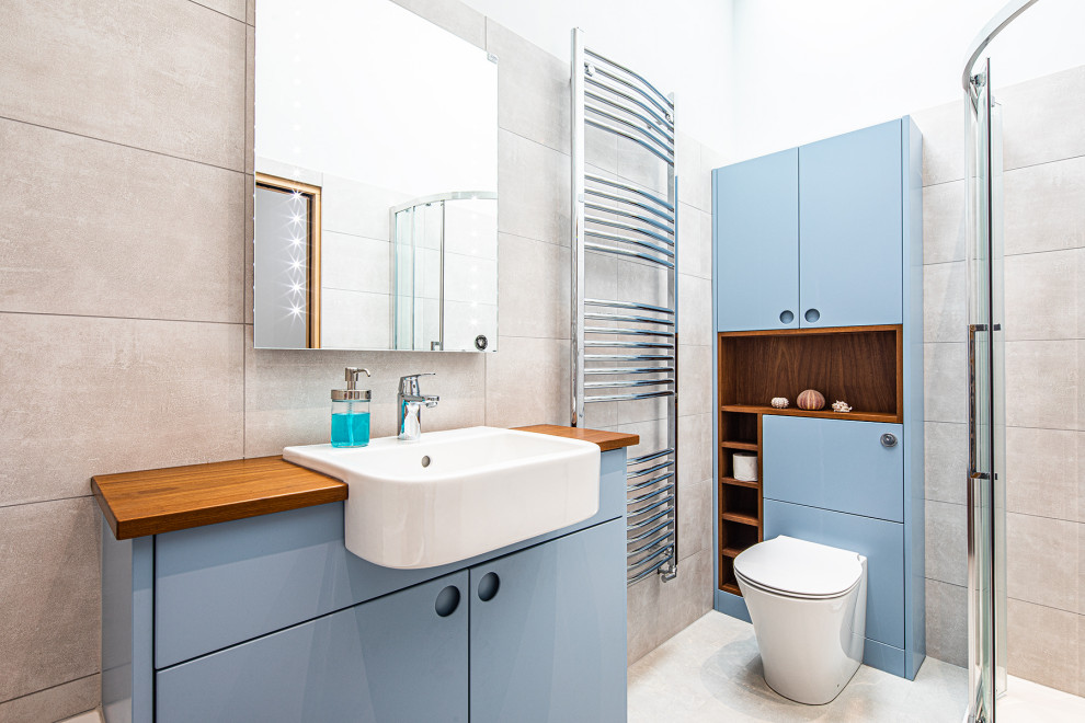 Inspiration för ett mellanstort funkis brun brunt badrum för barn, med blå skåp, grå kakel, grå väggar, träbänkskiva, grått golv och dusch med skjutdörr