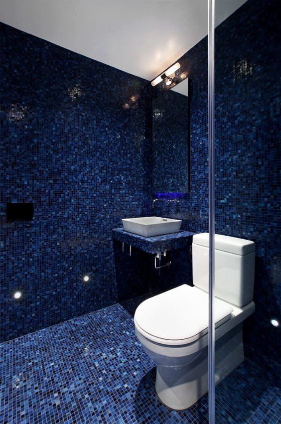 Modern inredning av ett litet badrum med dusch, med en toalettstol med separat cisternkåpa, blå kakel, mosaik, blå väggar, mosaikgolv, kaklad bänkskiva, ett fristående handfat och blått golv