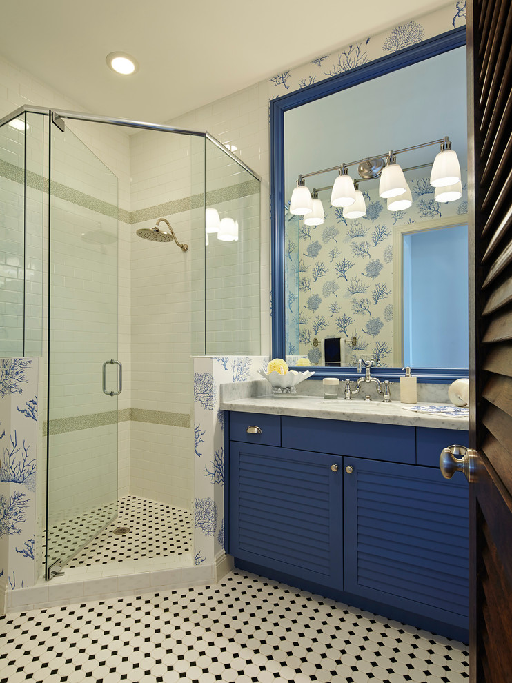 Exemple d'une salle de bain bord de mer avec un placard à porte persienne, des portes de placard bleues, une douche d'angle et du carrelage bicolore.