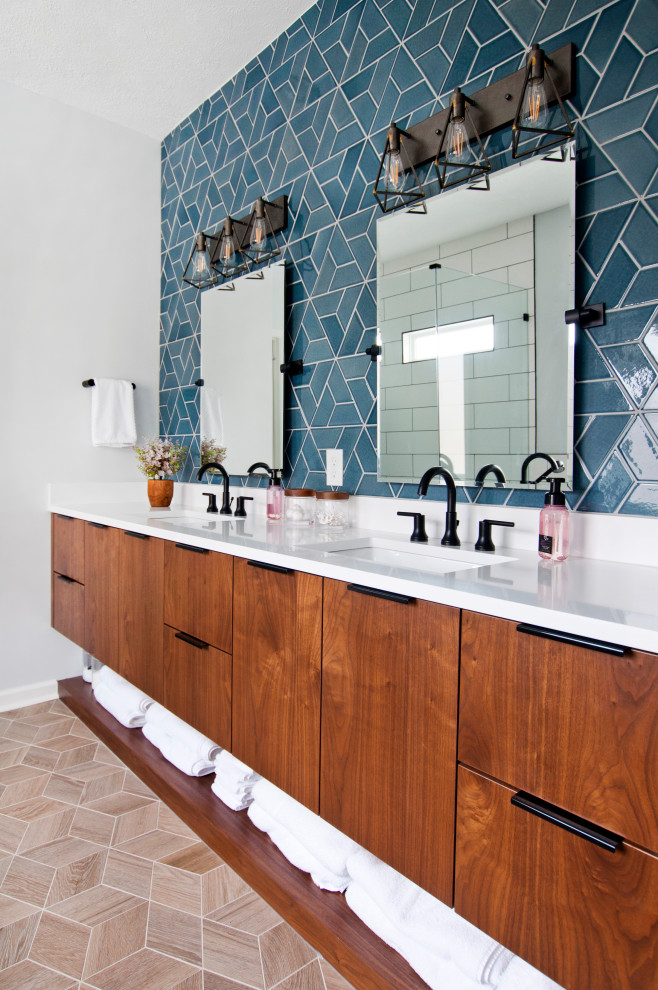 На фото: ванная комната в современном стиле с плоскими фасадами, фасадами цвета дерева среднего тона, синей плиткой, белыми стенами, врезной раковиной, бежевым полом, белой столешницей, тумбой под две раковины и подвесной тумбой